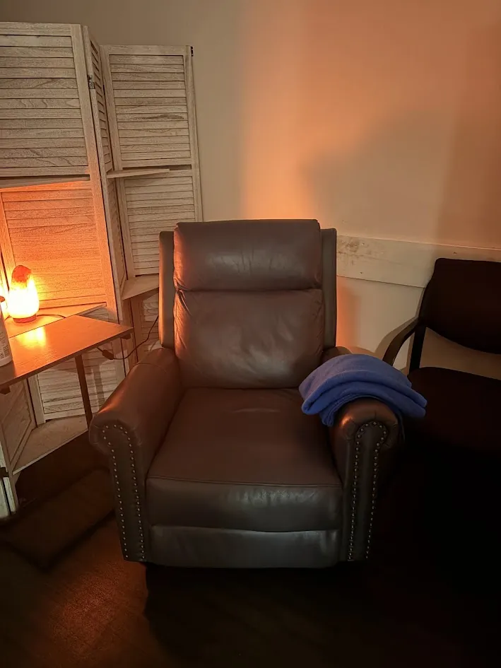 A leather recliner in one of our Bridgewater treatment spaces, a folded blue blanket over its arm and a salt lamp glowing on the side table.