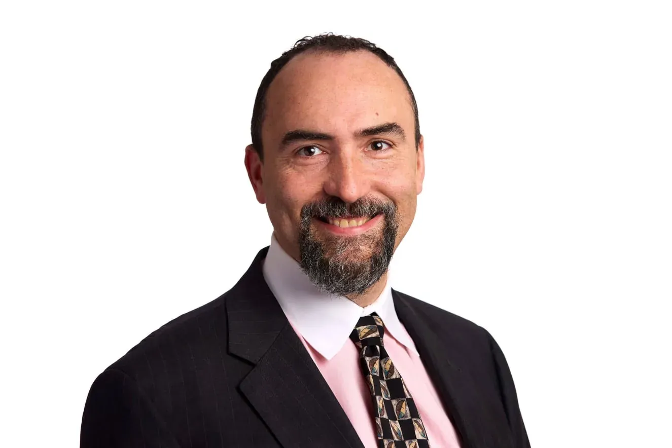 Dr. David Boguslavsky, smiling, in a dark pinstripe suit and patterned tie.