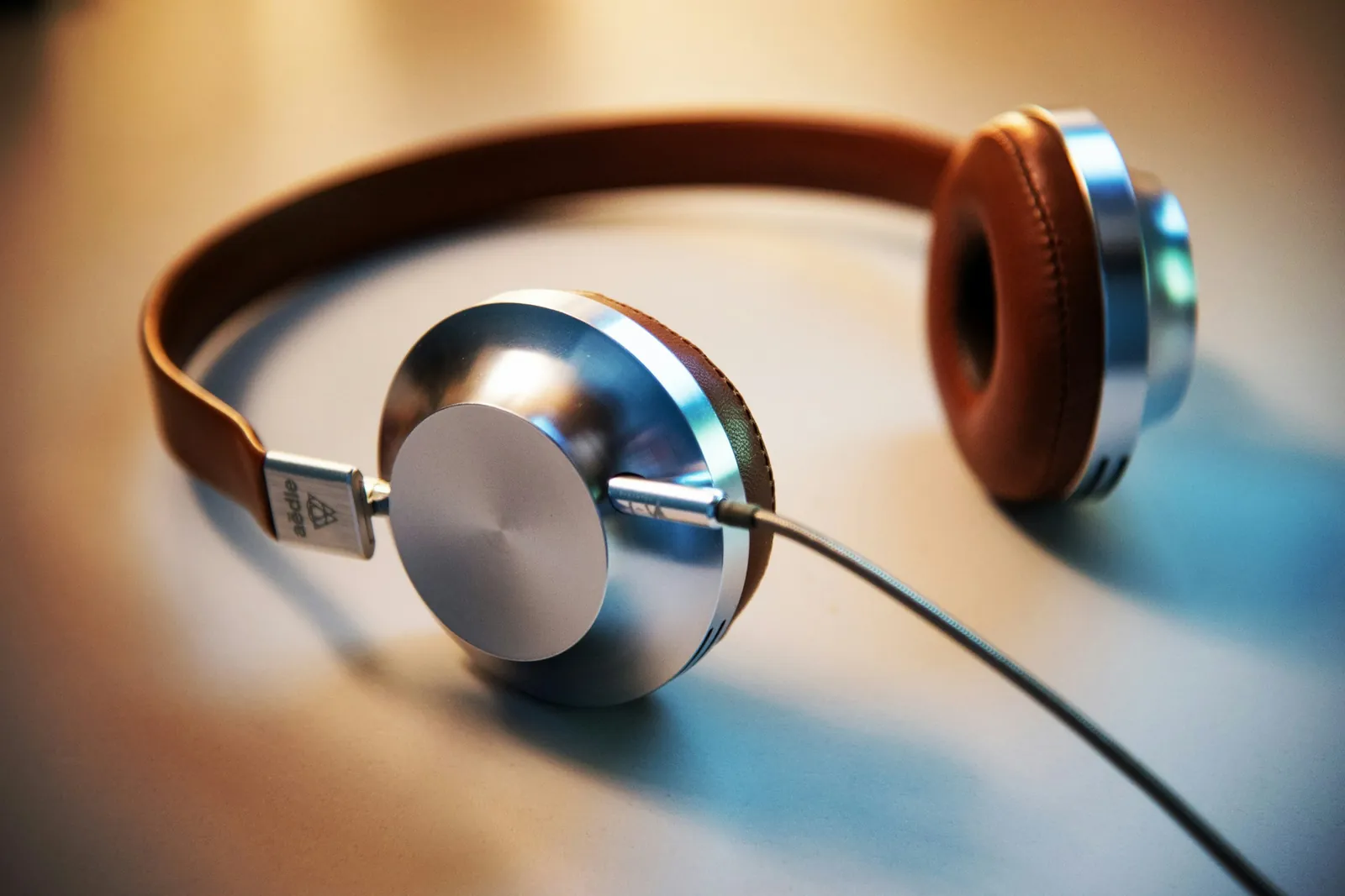 A pair of headphones resting on a table in warm light.