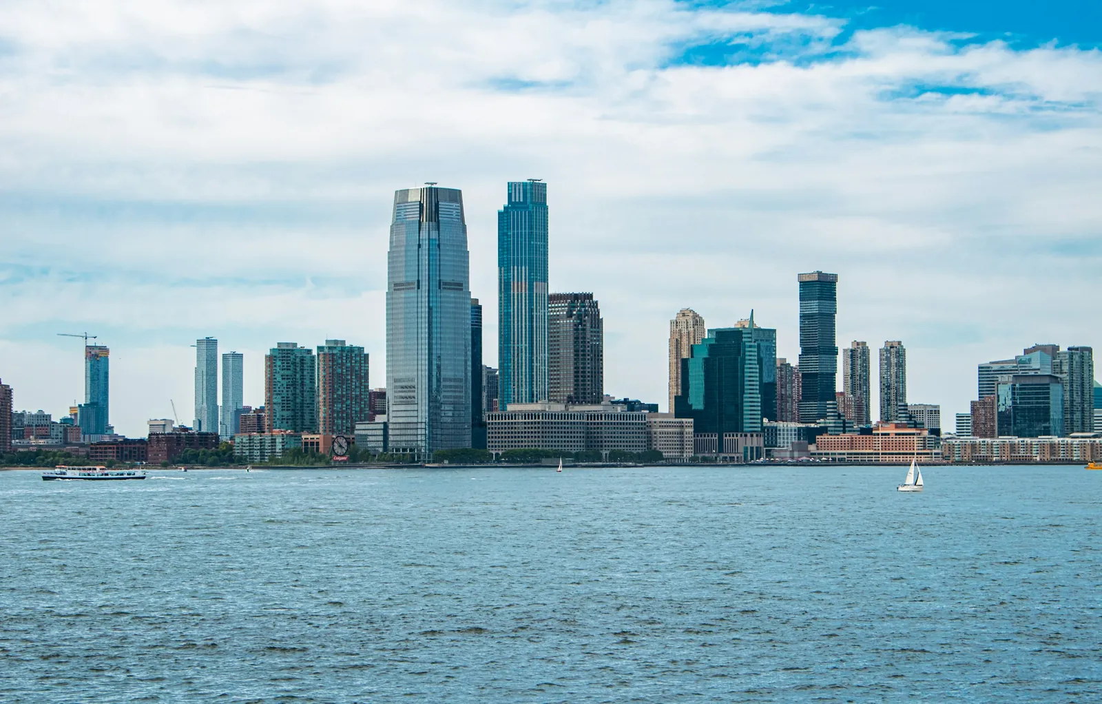 The Jersey City skyline seen across the water on a bright day.
