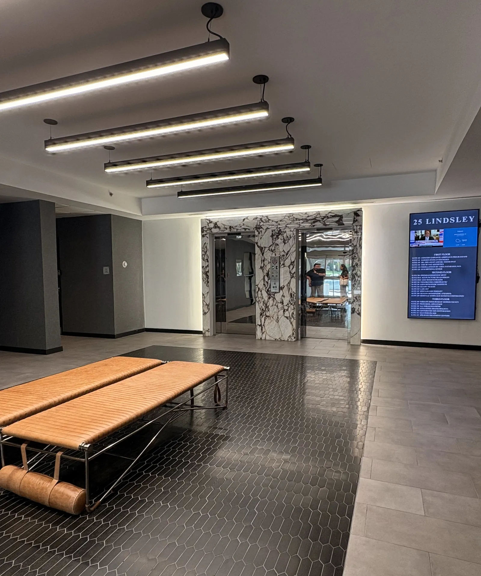 The lobby of 25 Lindsley Drive: a wooden bench, stone-clad walls and a building directory.