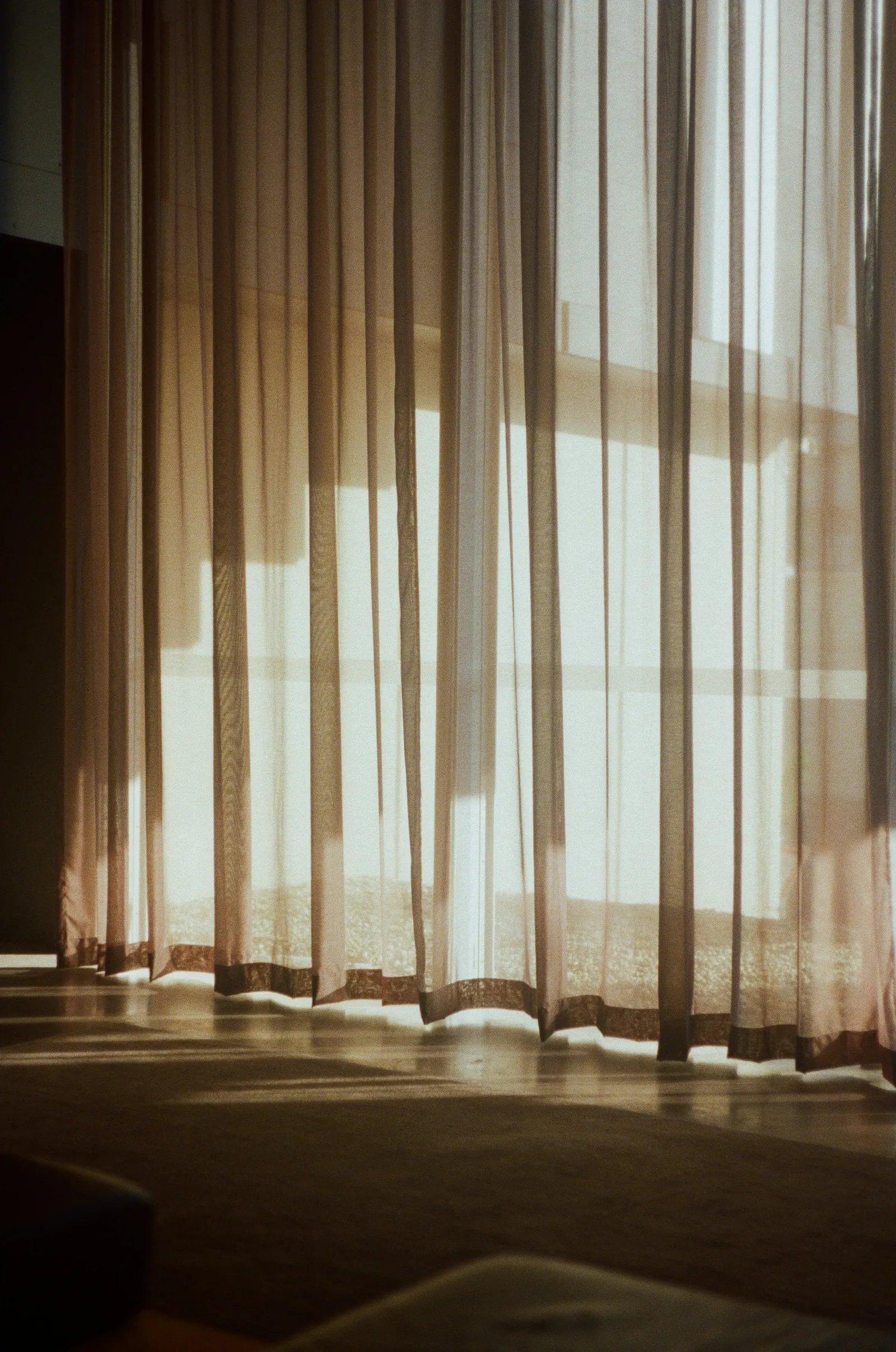 Sheer curtains glowing with soft light in a quiet room.