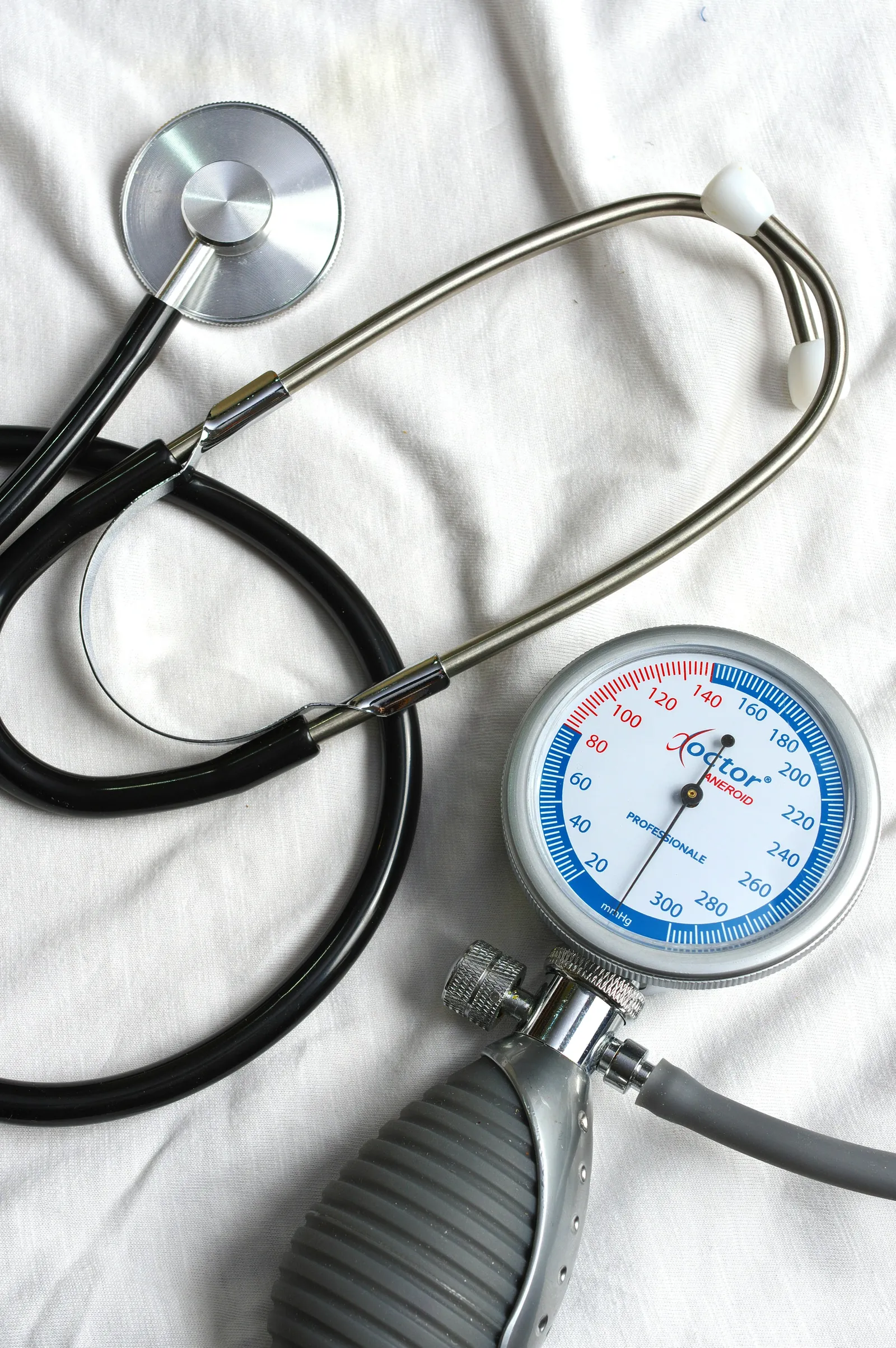 A stethoscope and a blood-pressure gauge resting on white fabric.